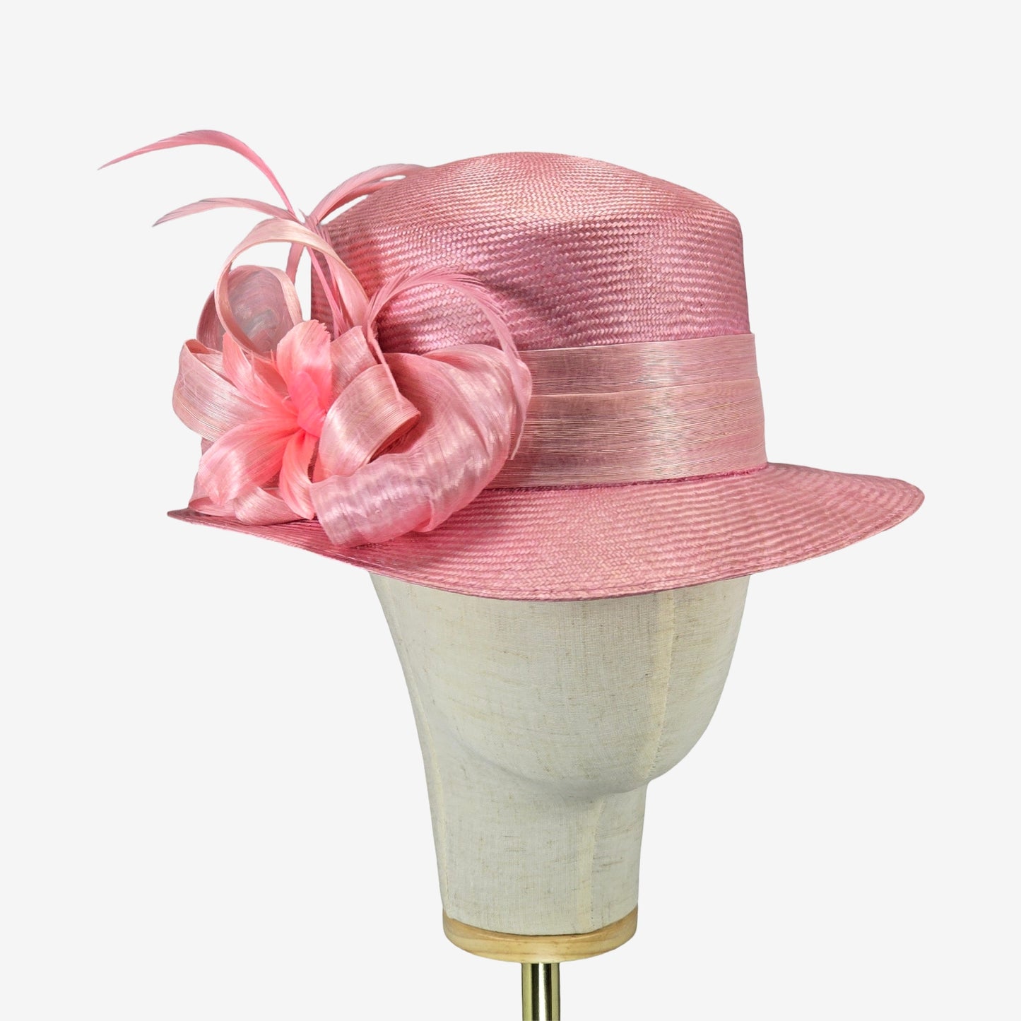 Pink straw hat with silk abaca trim on a mannequin head against a white background