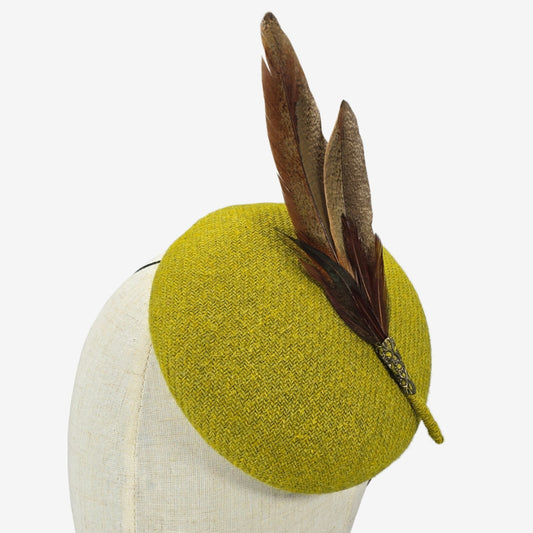 Green chartreuse pillbox hat with feather detail on a mannequin head against a white background
