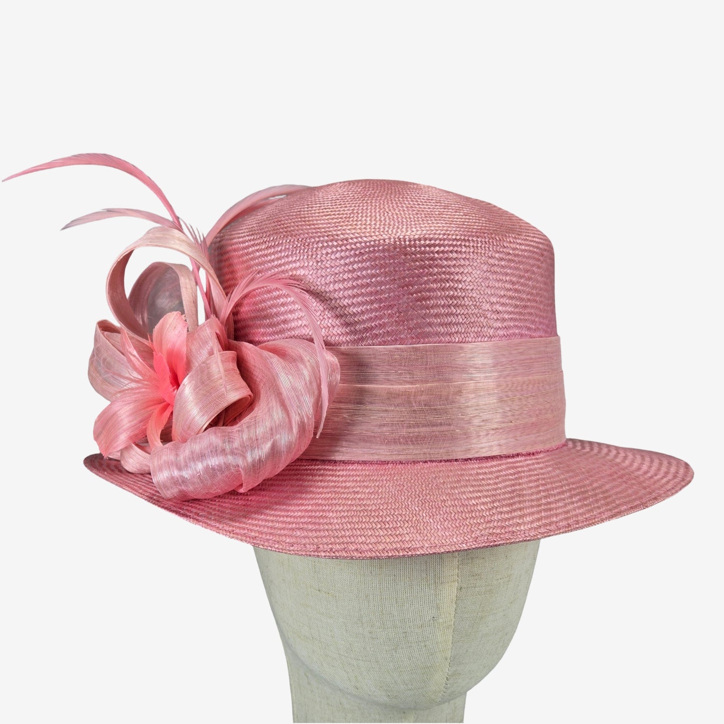 Pink straw hat with decorative silk abaca adornment on a mannequin head against a white background